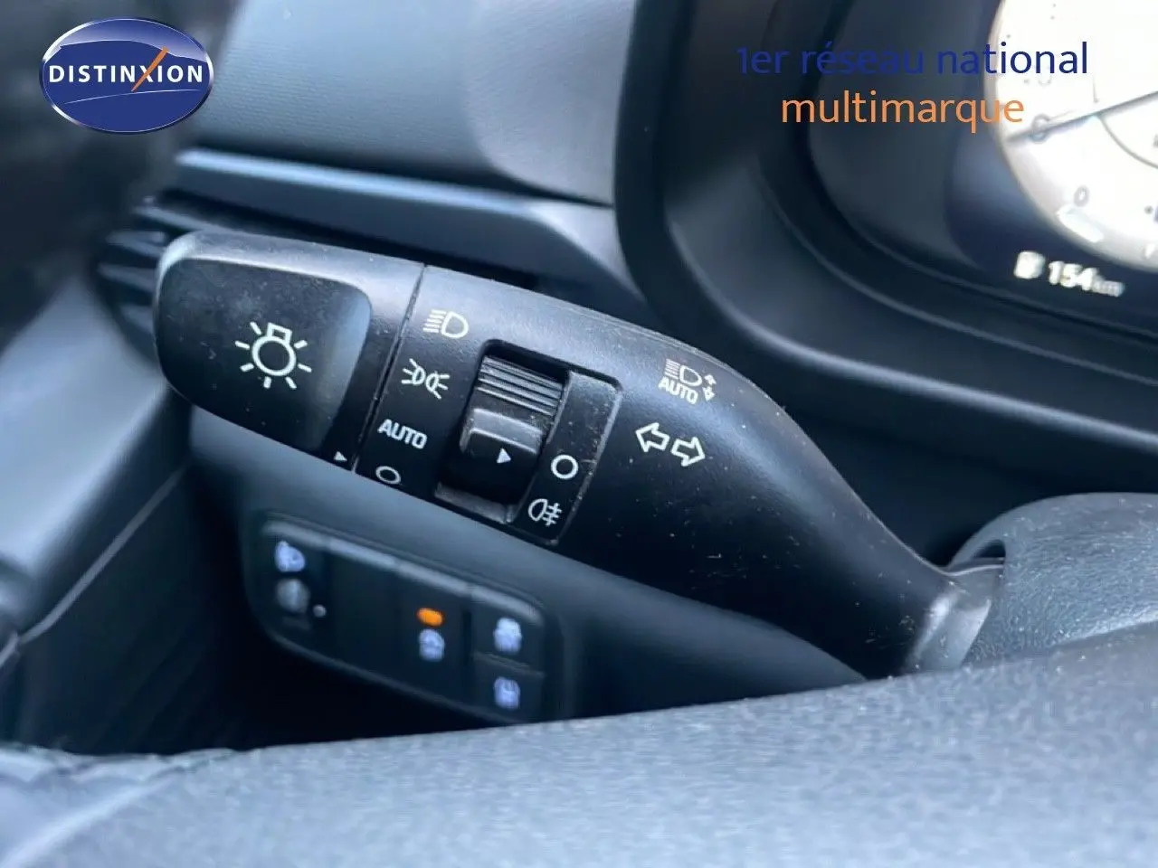 Gros plan sur la commande de clignotants et phares à gauche du volant dans l’habitacle d’une Hyundai i20 blanche.