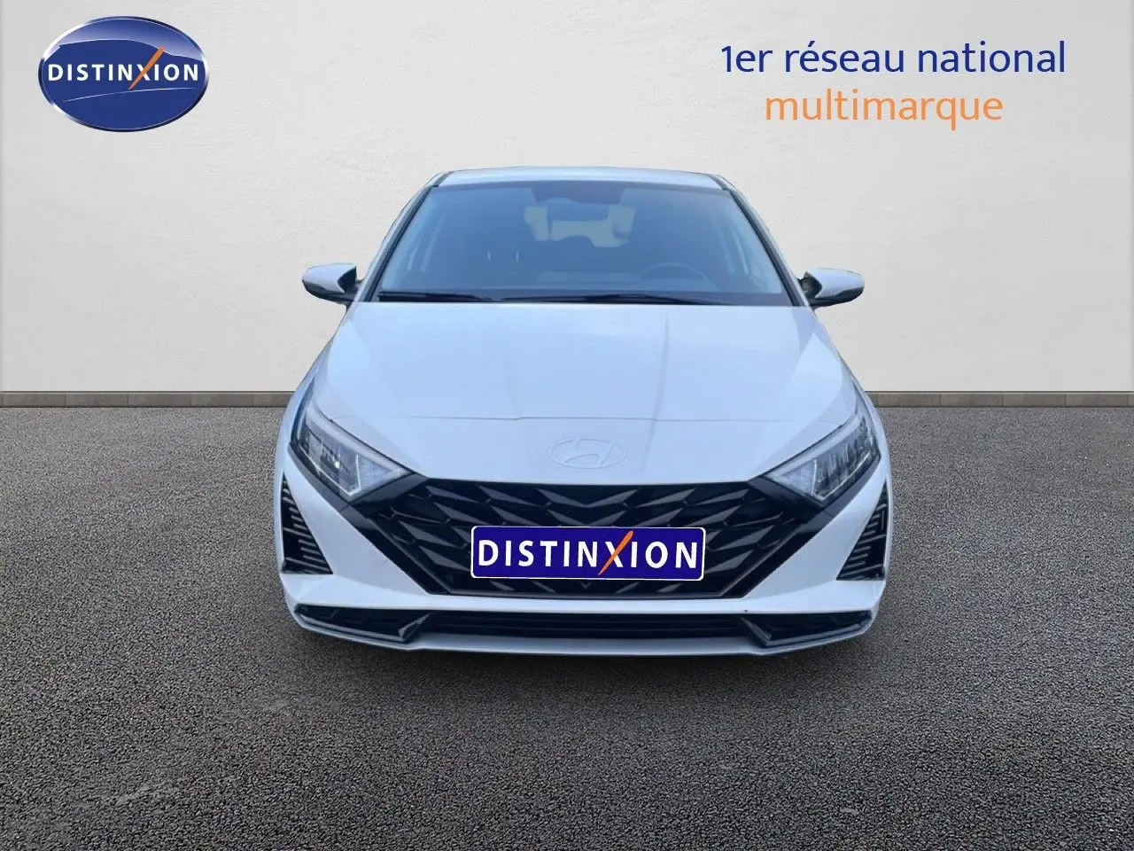 Vue frontale d'une Hyundai i20 2025 blanche Atlas avec calandre noire et phares LED distinctifs.