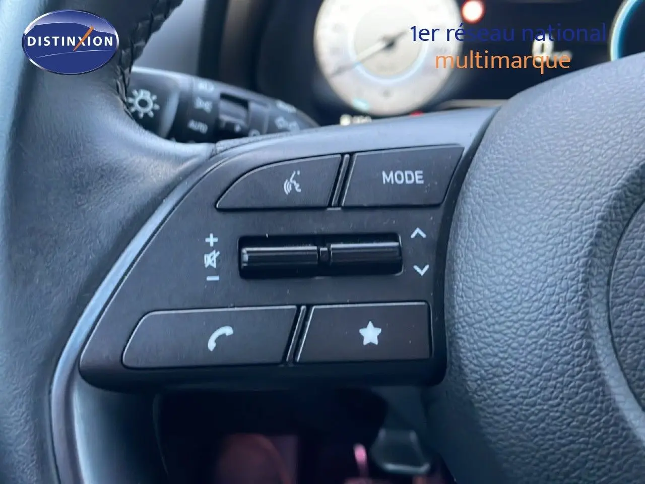 Gros plan sur les commandes multifonctions à gauche du volant en cuir noir d'une Hyundai i20 blanc atlas 2025.