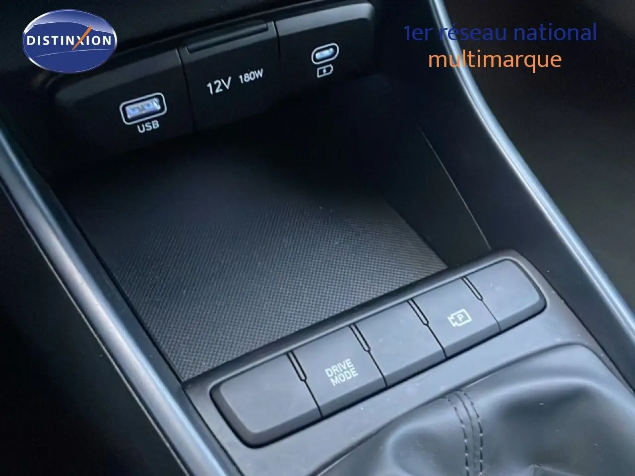 Gros plan sur la console centrale de la Hyundai i20 blanche avec boutons Drive Mode et frein à main électrique.