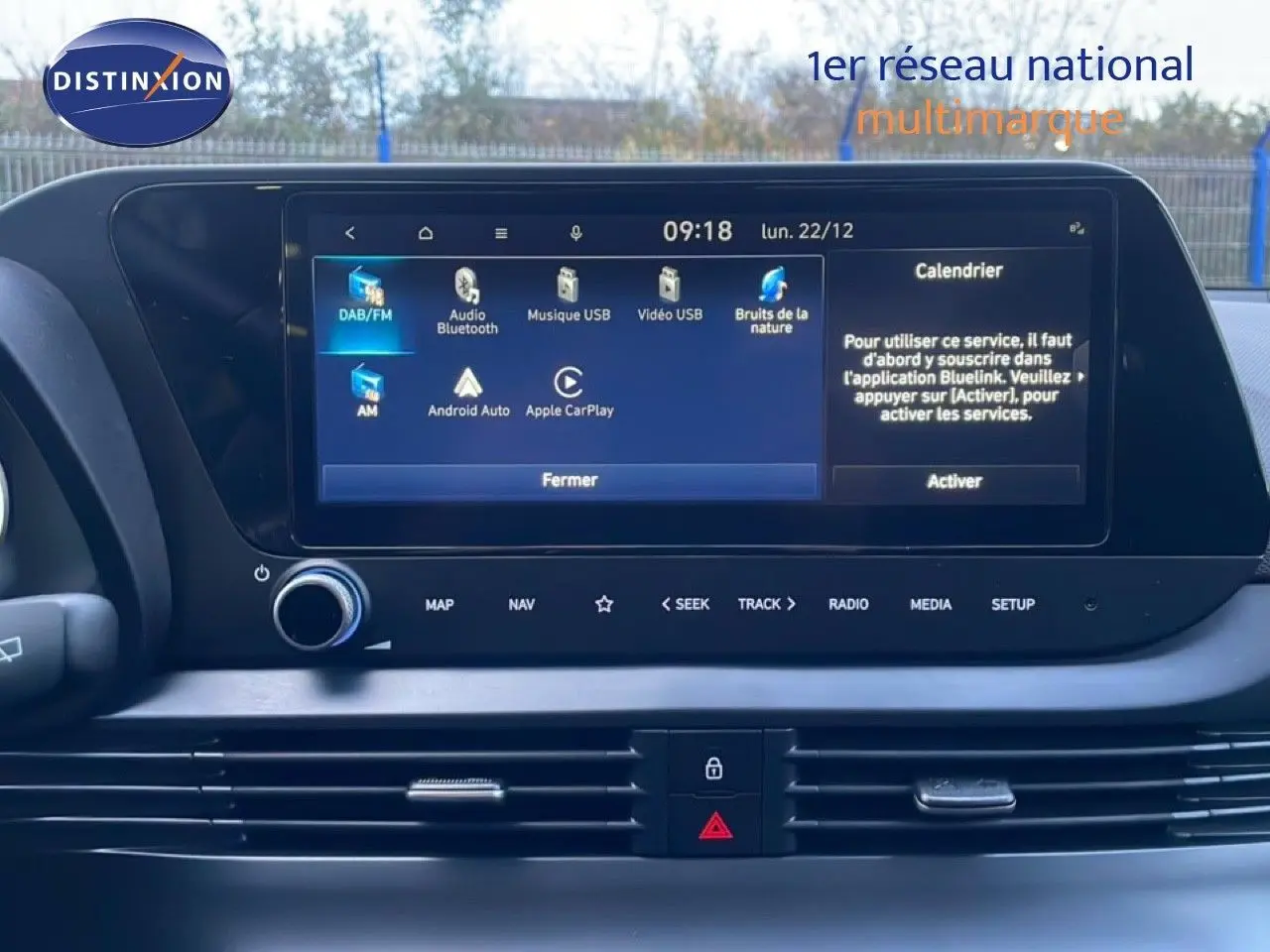 Vue rapprochée de l’écran tactile central de la Hyundai i20 blanche, affichant les options multimédia et connectivité.