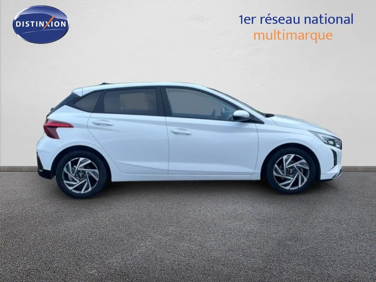 Profil droit d'une Hyundai i20 blanc atlas 2025 avec jantes alliage et vitres teintées, sur fond neutre.