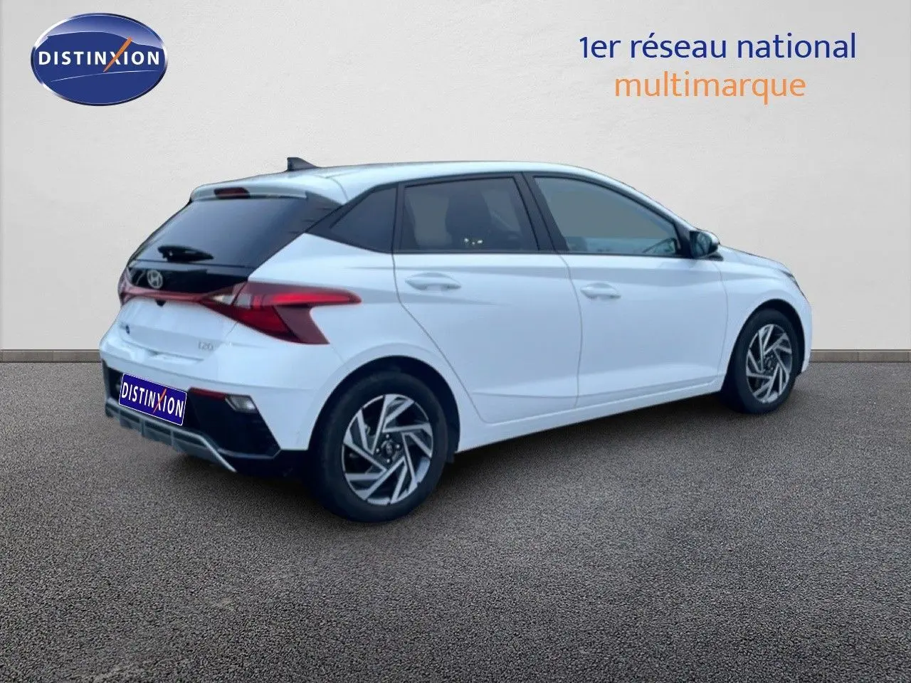 Vue 3/4 arrière droite d'une Hyundai i20 blanche Atlas avec toit noir et jantes alliage distinctives.