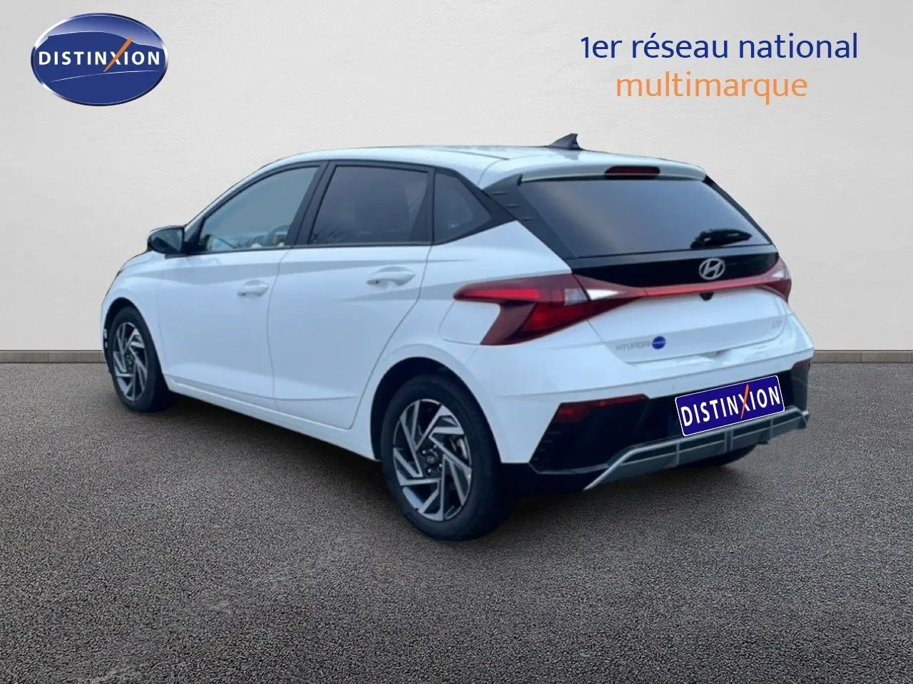 Vue 3/4 arrière droite d'une Hyundai i20 blanche Atlas avec feux arrière LED et jantes alliage distinctives.