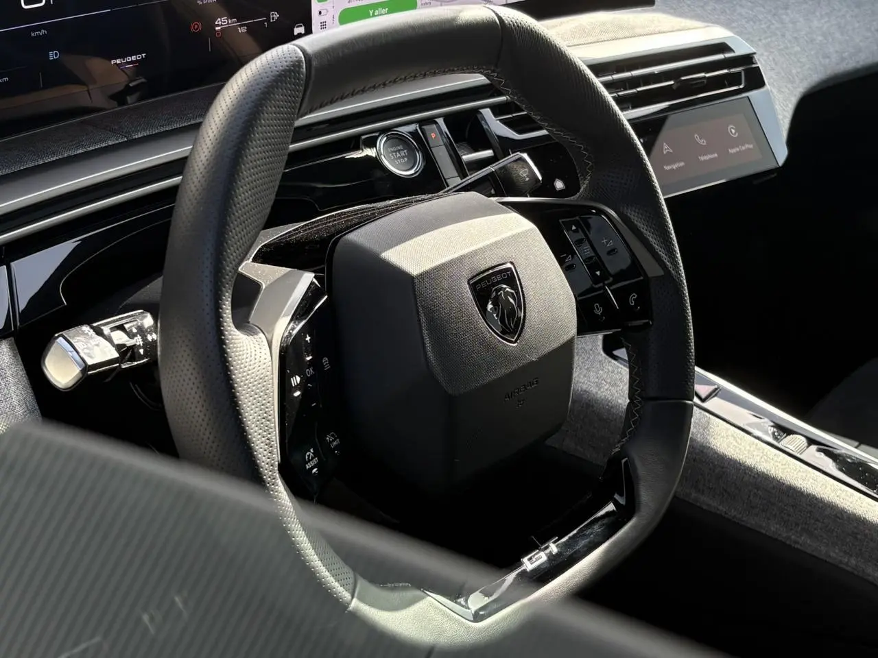 Gros plan sur le volant compact noir perforé avec badge GT du Peugeot 3008 Hybrid 2025, intérieur Alcantara gris.