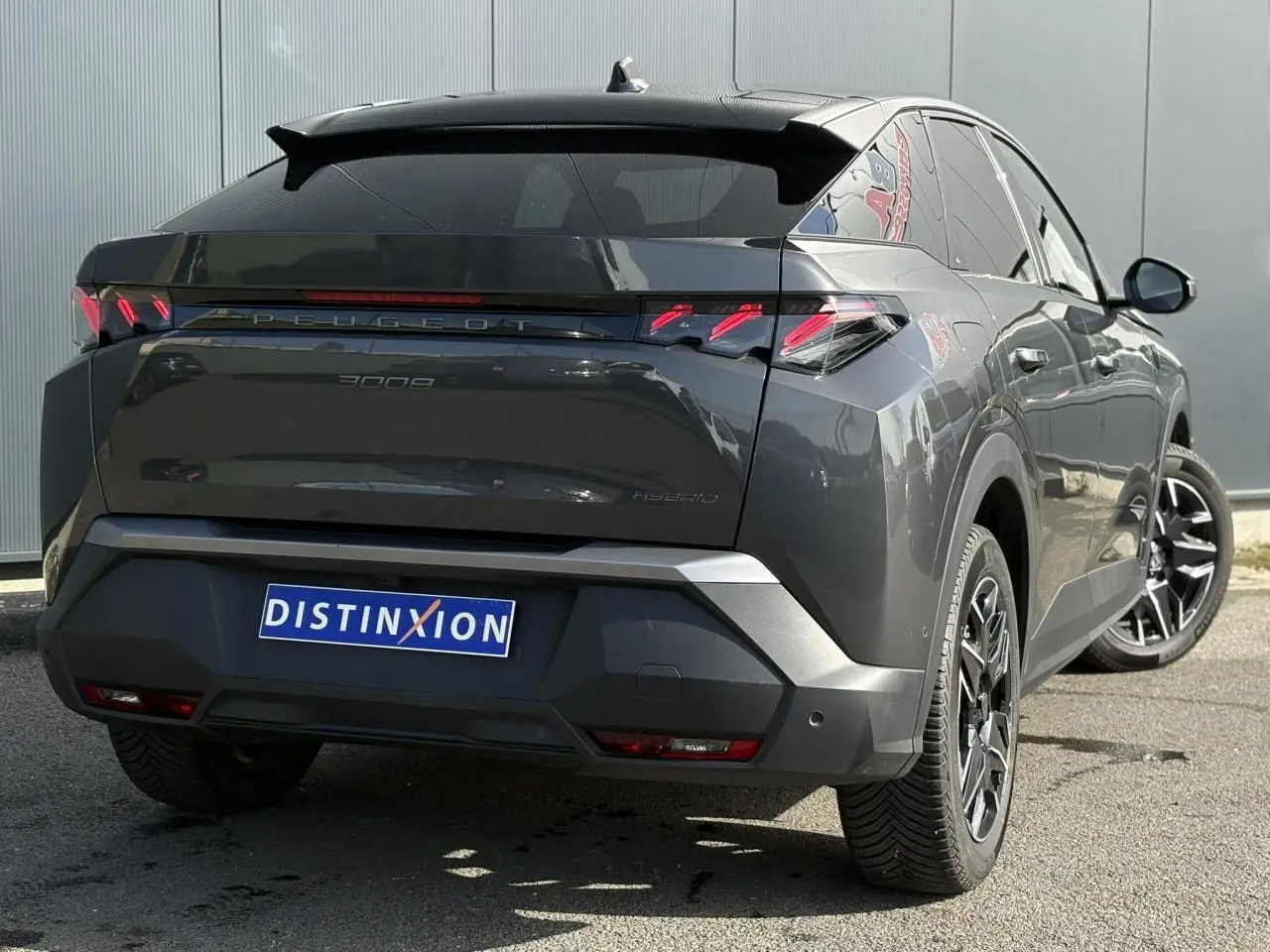 Vue 3/4 arrière droite du Peugeot 3008 Hybrid gris Titane avec jantes noires et feux arrière à griffes LED.