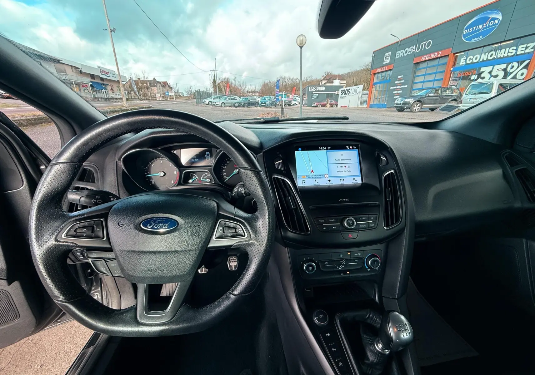 Gros plan sur la console centrale noire de la Ford Focus 1.5 TDCI 120 ST Line, montrant les boutons de stationnement et démarrage.