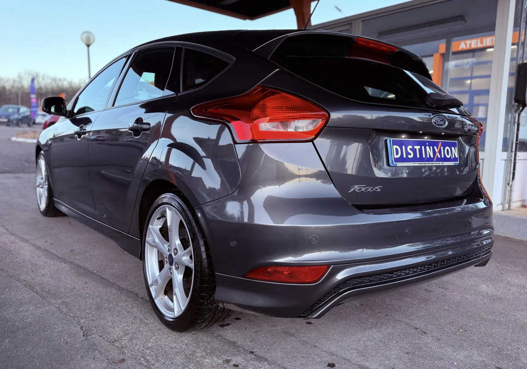 Vue 3/4 arrière droite d'une Ford Focus gris métallisé 2018 avec jantes alliage et hayon fermé.