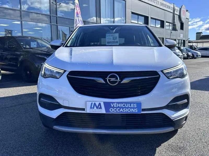 Vue avant d’un Opel Grandland X blanc 2018, avec calandre noire et logo Opel bien visible, sur parking extérieur.