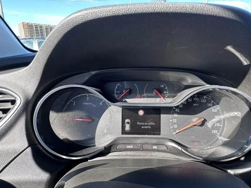 Vue rapprochée du tableau de bord de l'Opel Grandland X 1.6 D 120 Innovation, affichant les compteurs et un message d'alerte.