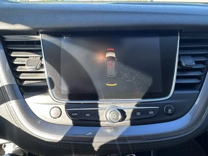 Écran central tactile de l’Opel Grandland X blanc 2018 affichant l’alerte de proximité avec commandes audio et navigation visibles.