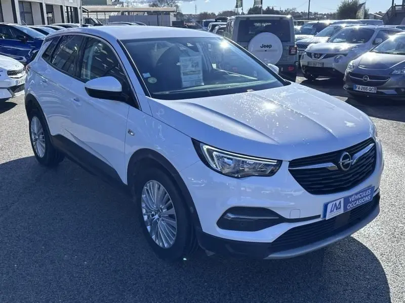 Vue 3/4 avant d’un Opel Grandland X blanc 2018 avec calandre noire et jantes alliage, stationné en extérieur.