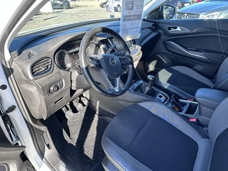 Intérieur avant droit d’un Opel Grandland X blanc 2018, volant multifonction, boîte manuelle et sièges tissu noirs.