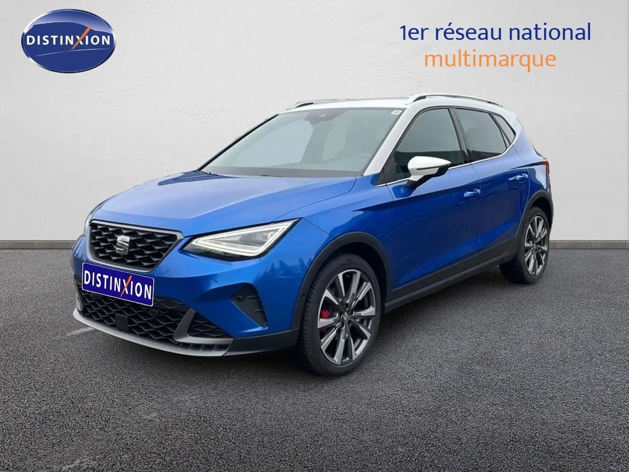 SEAT Arona 2025 bleu saphir métal avec toit blanc, vue 3/4 avant droit, jantes alliage et calandre distinctive.