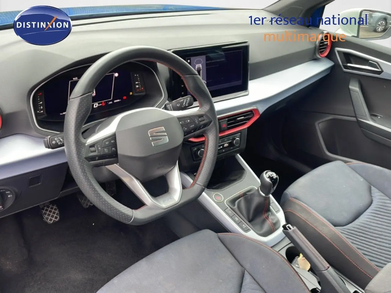 Vue intérieure de face du poste de conduite du SEAT Arona 2025, volant cuir multifonction et levier de vitesse manuel.