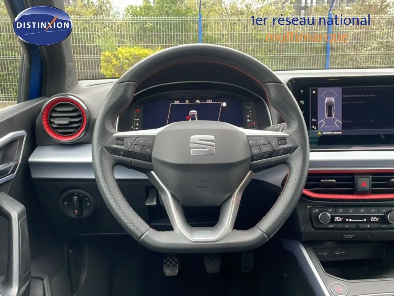 Vue intérieure centrée sur le volant perforé de la SEAT Arona 2025, avec détails rouges et écran numérique visible.