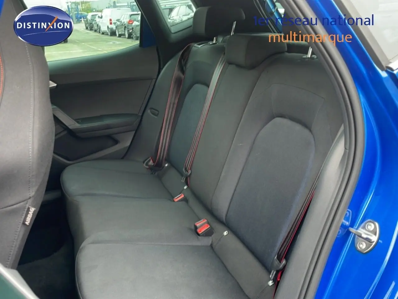 Vue intérieure côté droit sur la banquette arrière en tissu noir avec ceinture rouge d’un SEAT Arona bleu saphir 2025.
