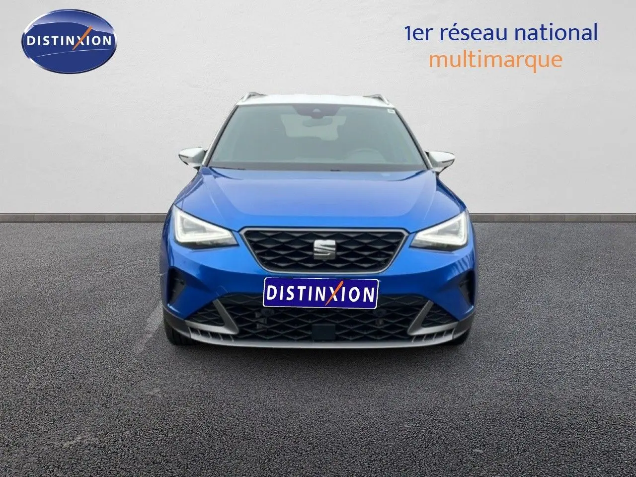 Vue frontale d'un SEAT Arona 2025 bleu saphir métal avec toit blanc et calandre noire distinctive.