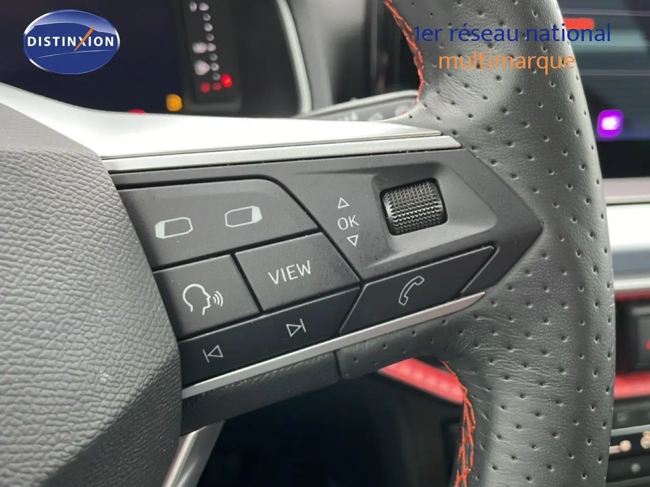 Gros plan sur les commandes gauche du volant en cuir perforé noir avec surpiqûres rouges du SEAT Arona 2025.