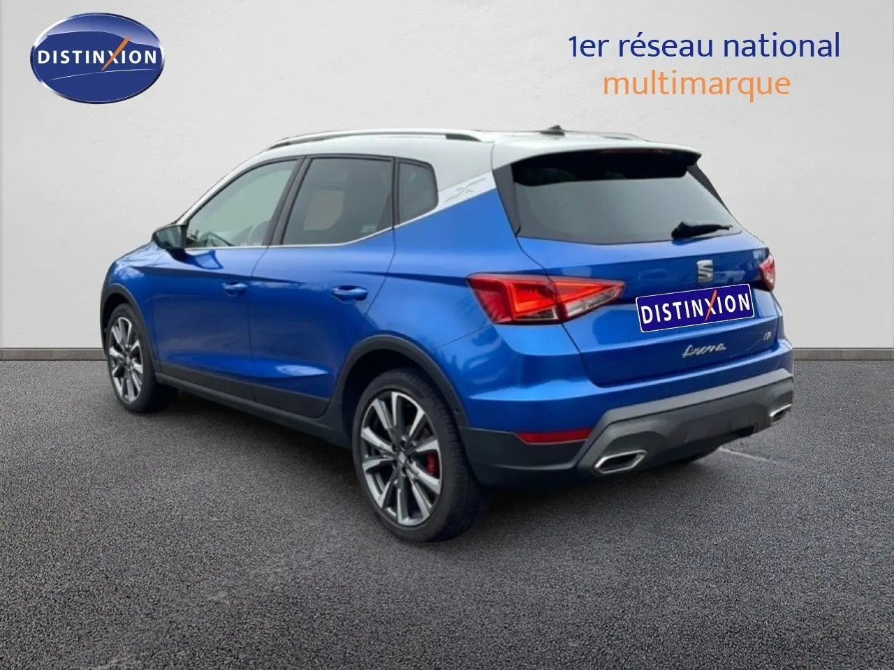 SEAT Arona bleu saphir métal avec toit blanc, vue 3/4 arrière droit, jantes alliage et feux arrière LED visibles.