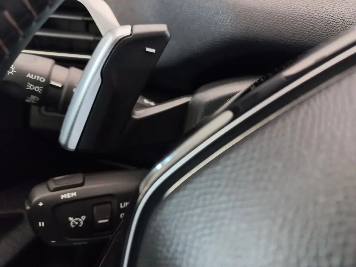 Gros plan sur les commandes au volant cuir noir du Peugeot 3008 PureTech 130, avec régulateur de vitesse et palettes.
