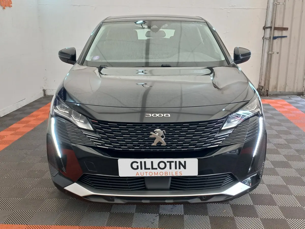 Vue avant d’un Peugeot 3008 noir 2022 avec calandre distinctive et feux LED en forme de griffes allumés.