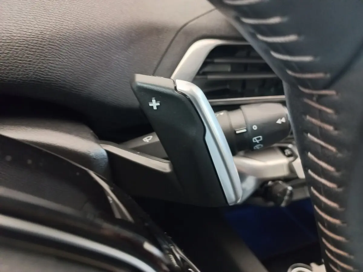 Gros plan sur la palette de changement de vitesse droite noire et argentée dans l’habitacle du Peugeot 3008 noir 2022.