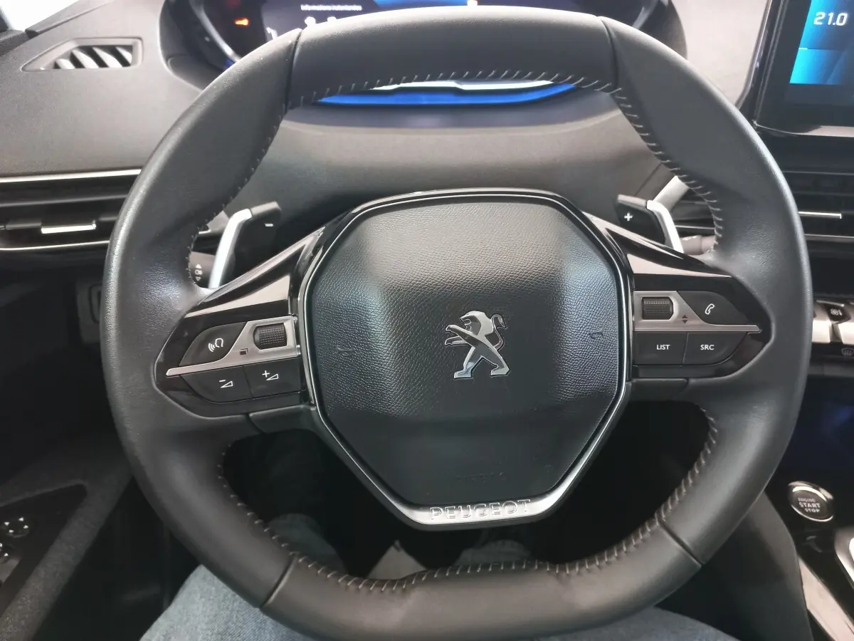 Vue rapprochée du volant cuir noir de la Peugeot 3008 avec commandes multifonctions et logo lion central.