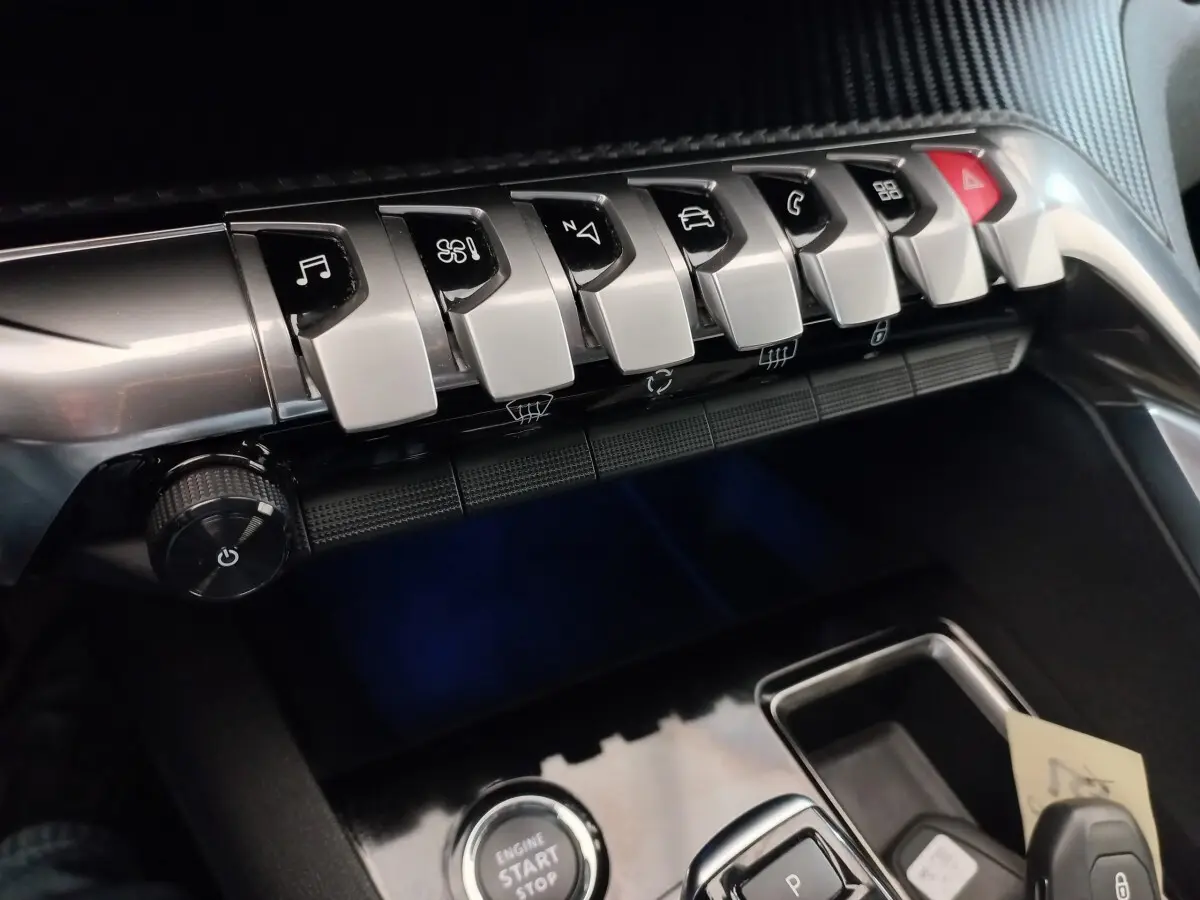 Gros plan sur la console centrale du Peugeot 3008 noir, montrant les boutons de commande et le bouton démarrage.