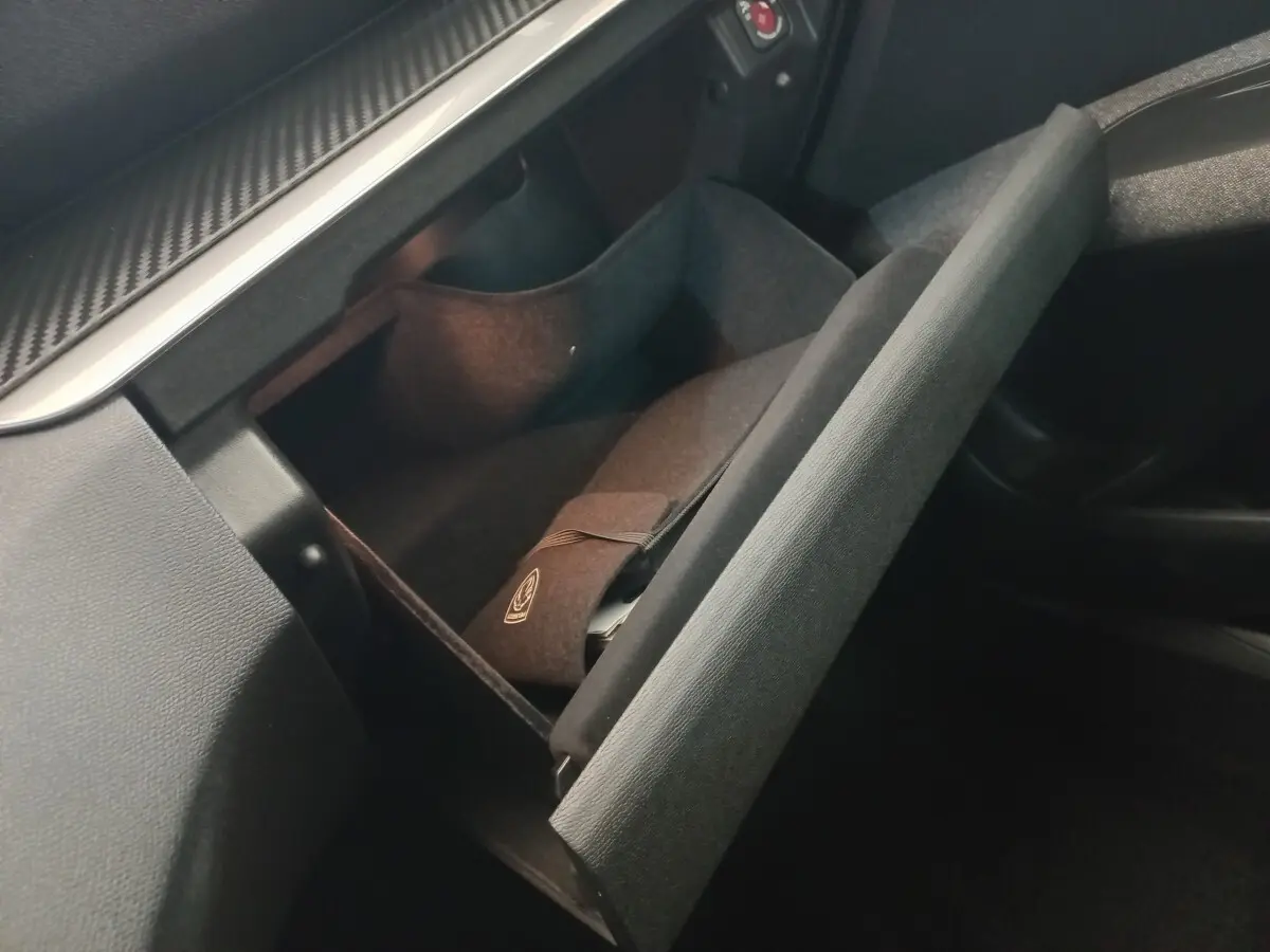 Vue intérieure du vide-poche passager ouvert du Peugeot 3008 noir 2022, avec pochette et éclairage doux.