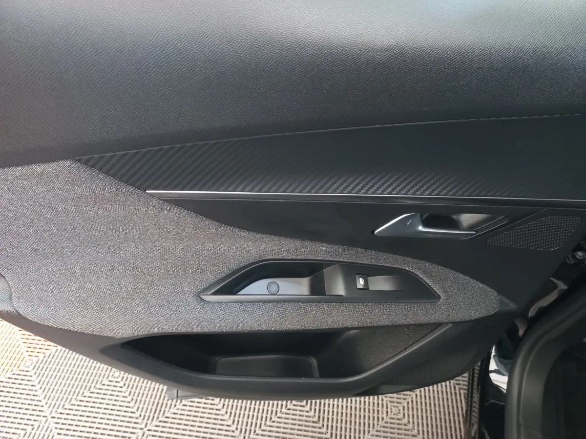 Gros plan sur la porte intérieure côté gauche du Peugeot 3008 noir, montrant la poignée et les commandes de fenêtre.