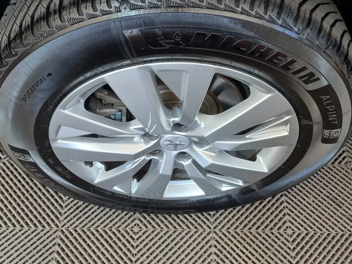 Gros plan sur la jante argentée et le pneu Michelin d'un Peugeot 3008 noir, vue de dessus.