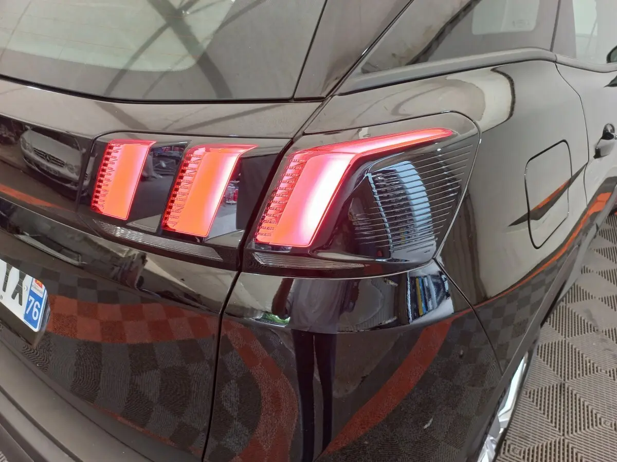 Gros plan sur le feu arrière droit rouge vif d’un Peugeot 3008 noir, mettant en valeur la carrosserie brillante.