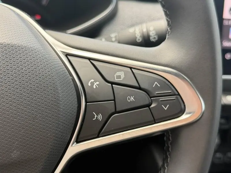 Gros plan sur les commandes multifonctions noires du volant de la Renault Clio gris schiste, finition Techno 2025.