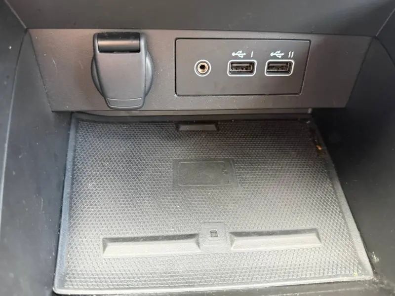 Vue rapprochée de la prise USB, prise jack et prise 12V dans le rangement central noir de la Renault Clio gris schiste.