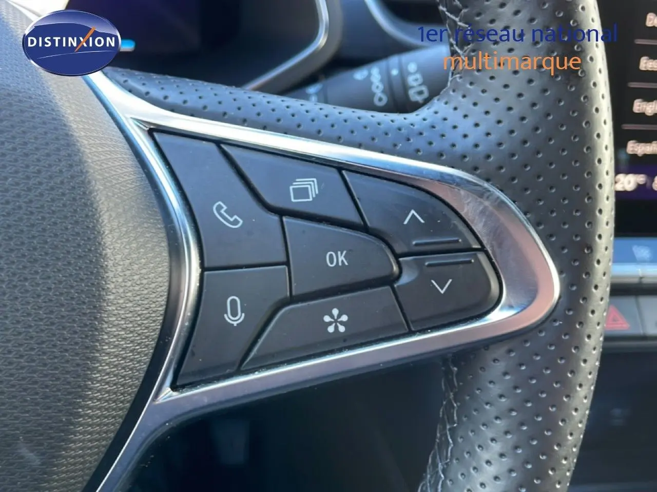 Gros plan sur les commandes multifonctions à gauche du volant en cuir perforé du Renault Symbioz bleu Iron Metal.
