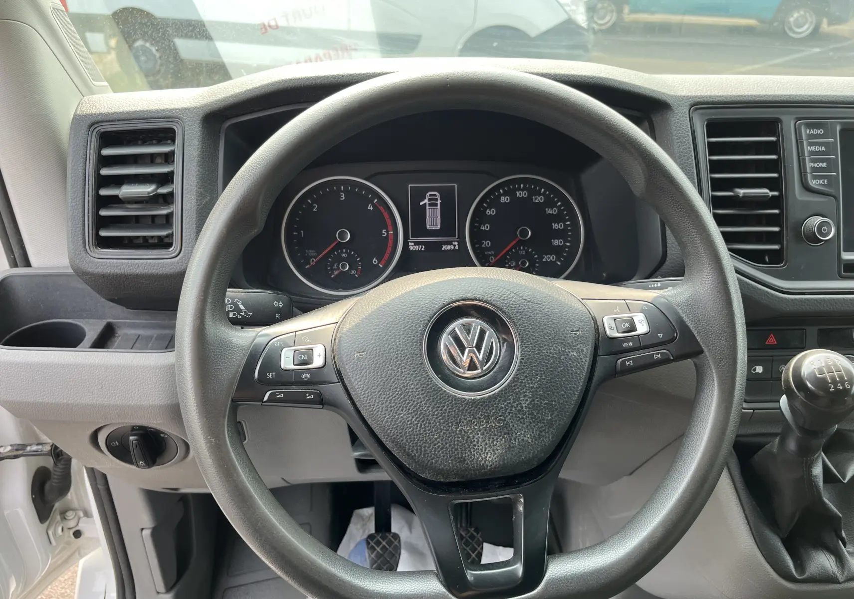 Vue intérieure du tableau de bord et volant noir du Volkswagen Crafter Fourgon 2019 avec boîte manuelle et affichage digital.