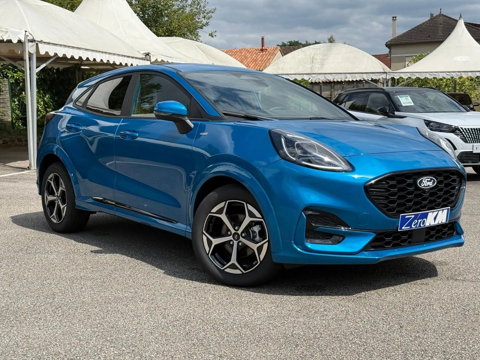 Ford Puma 2025 bleu Aqua Blue en 3/4 avant droit, avec jantes alliage et calandre noire distinctive.
