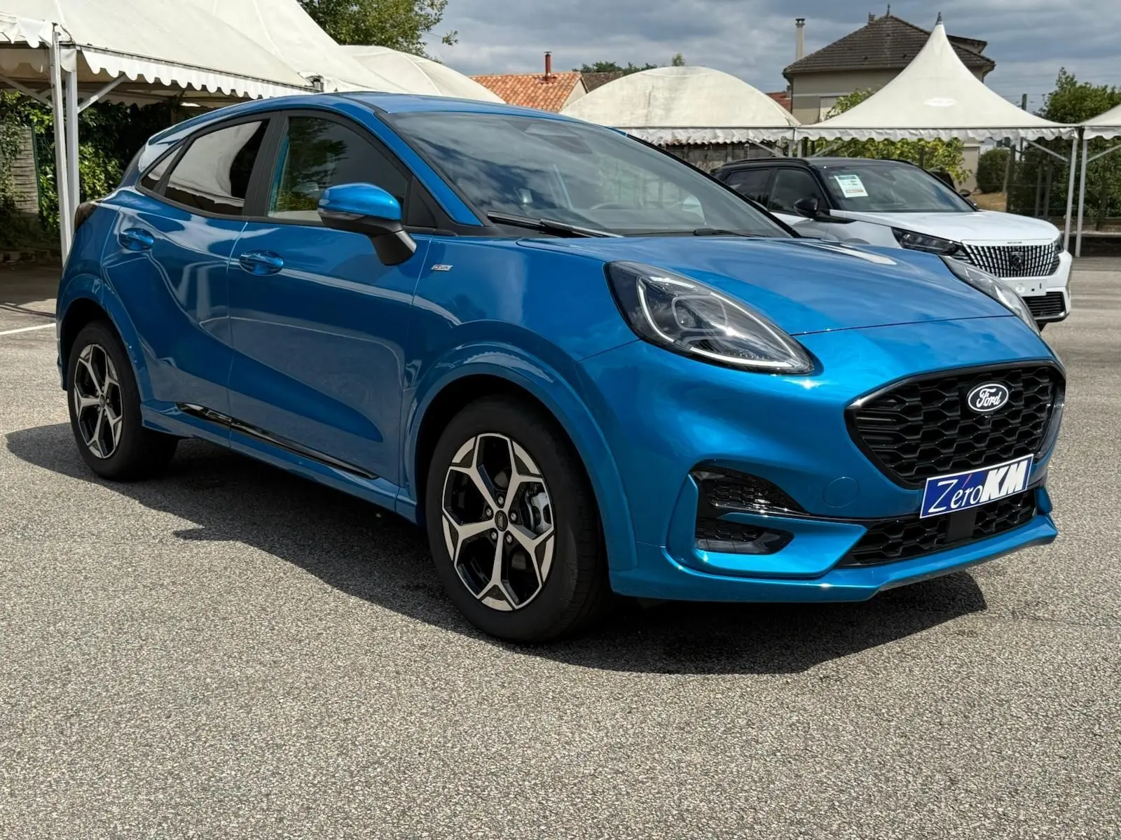 Ford Puma 2025 bleu Aqua Blue en 3/4 avant droit, avec calandre noire et jantes alliage distinctives ST Line.