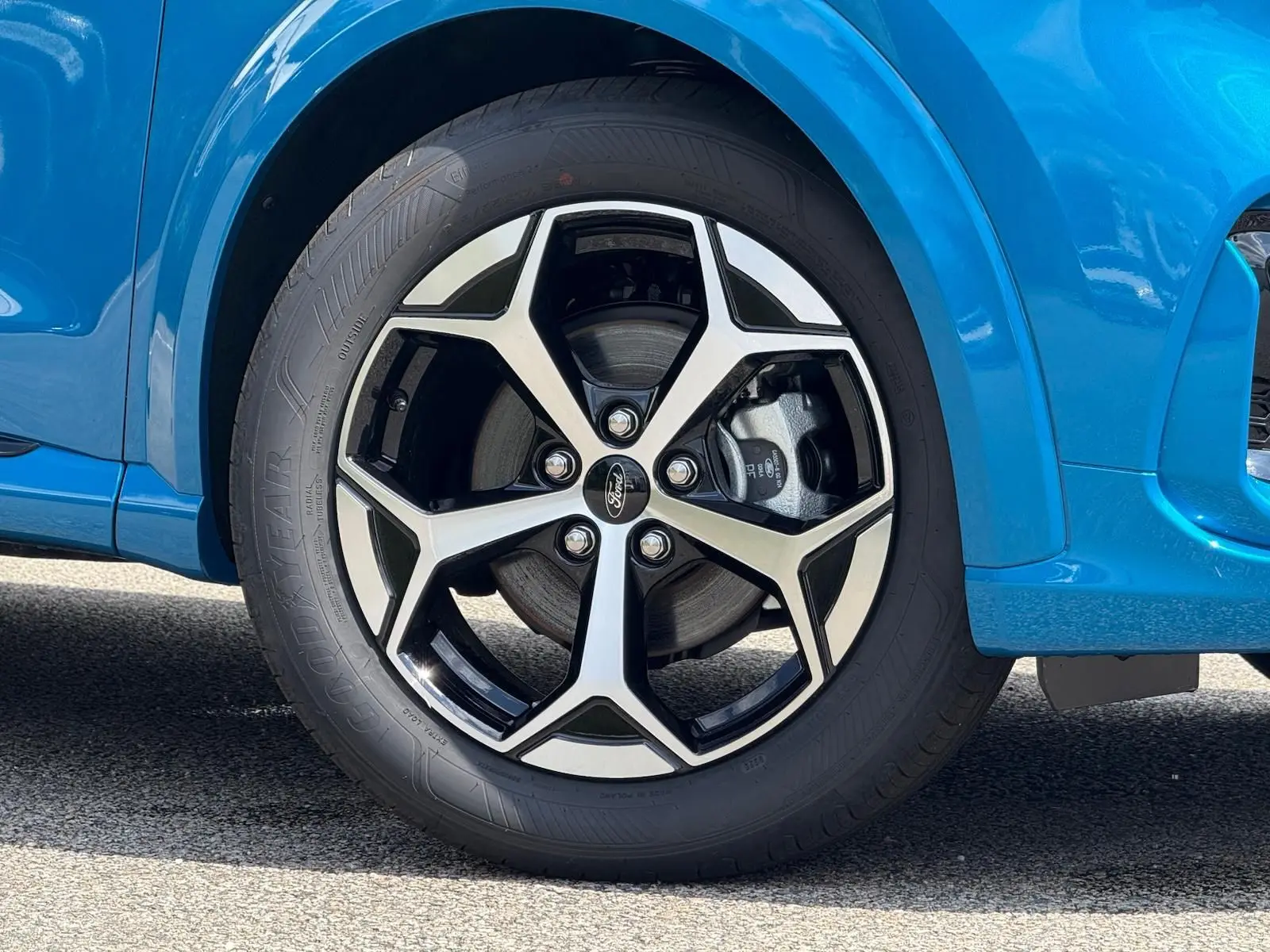 Gros plan sur la roue avant droite du Ford Puma bleu Aqua Blue avec jante alliage noire et argentée.