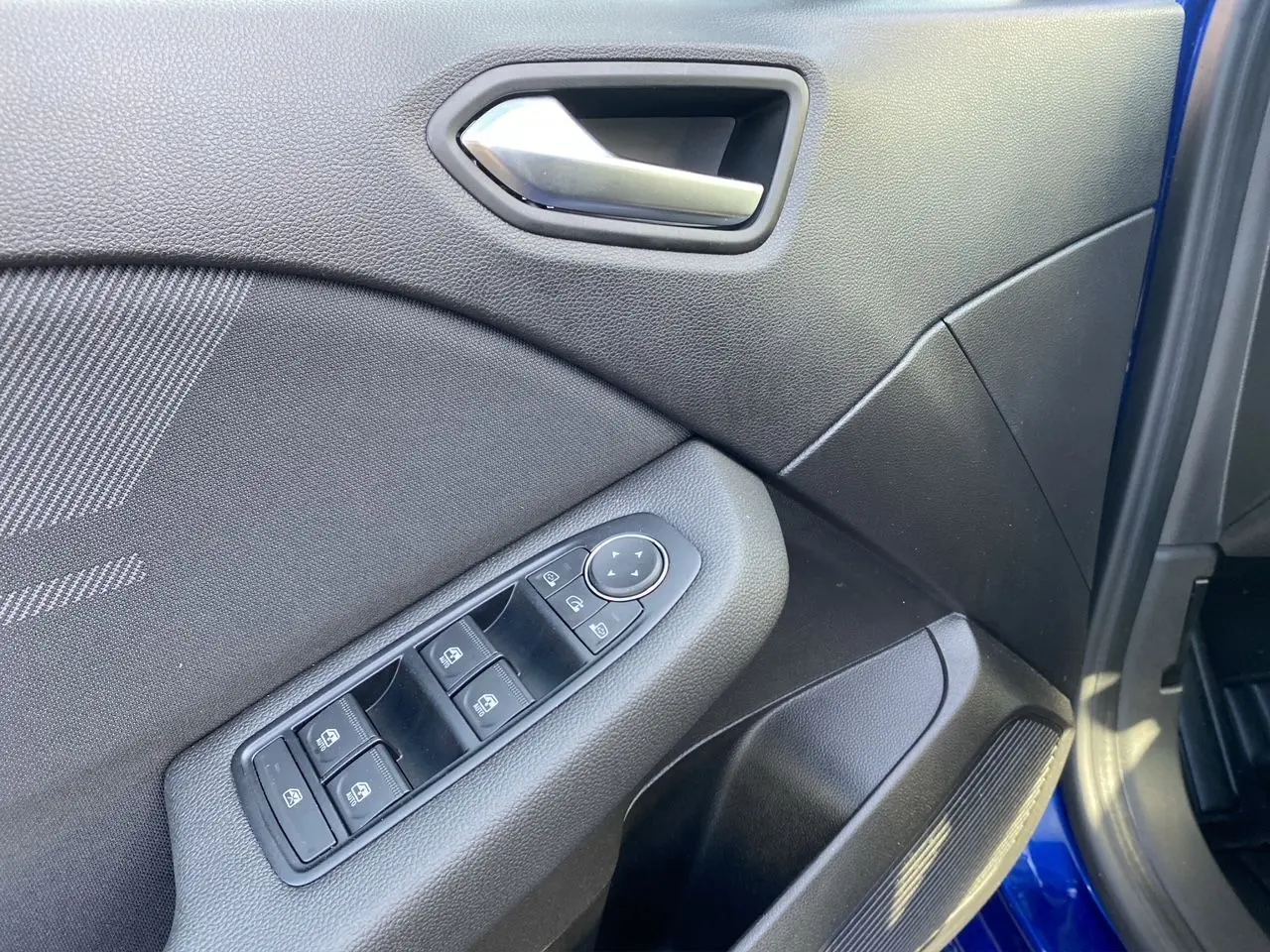 Intérieur de la porte avant gauche d'une Renault Clio V Bleu Iron, avec commandes électriques et poignée argentée.
