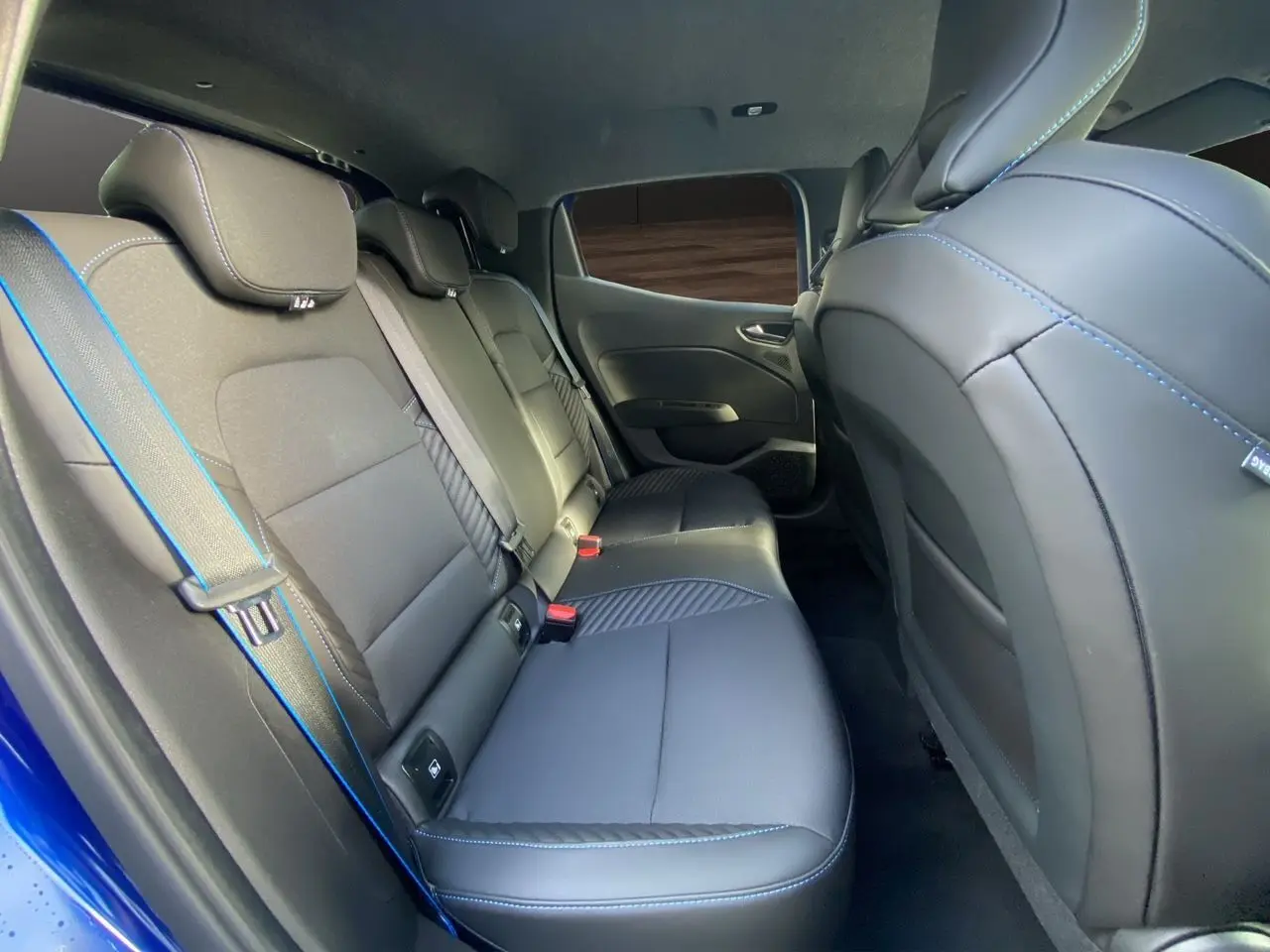 Vue intérieure arrière de la Renault Clio V TCE 90 Esprit Alpine bleu Iron, sièges noirs avec surpiqûres bleues.