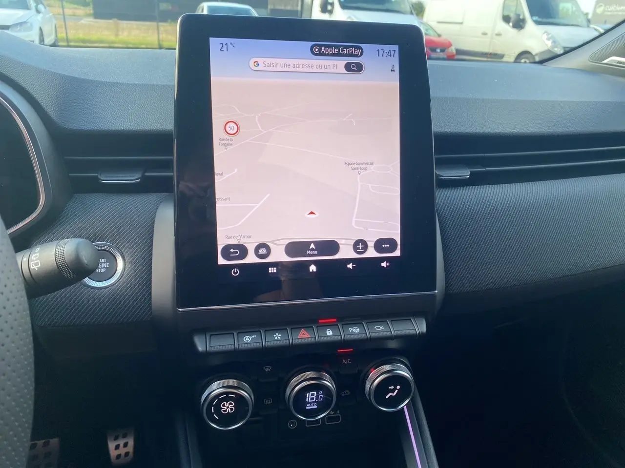 Tableau de bord de Renault Clio V bleu Iron 2025 avec écran tactile central affichant la navigation et commandes de climatisation.