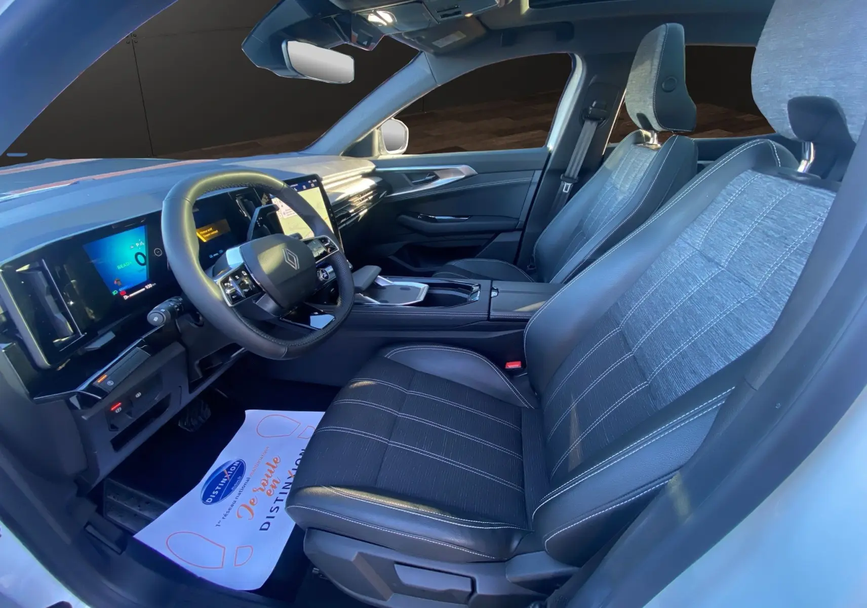 Vue intérieure côté conducteur du Renault Austral 2025, sièges tissu et cuir noirs, toit panoramique visible.