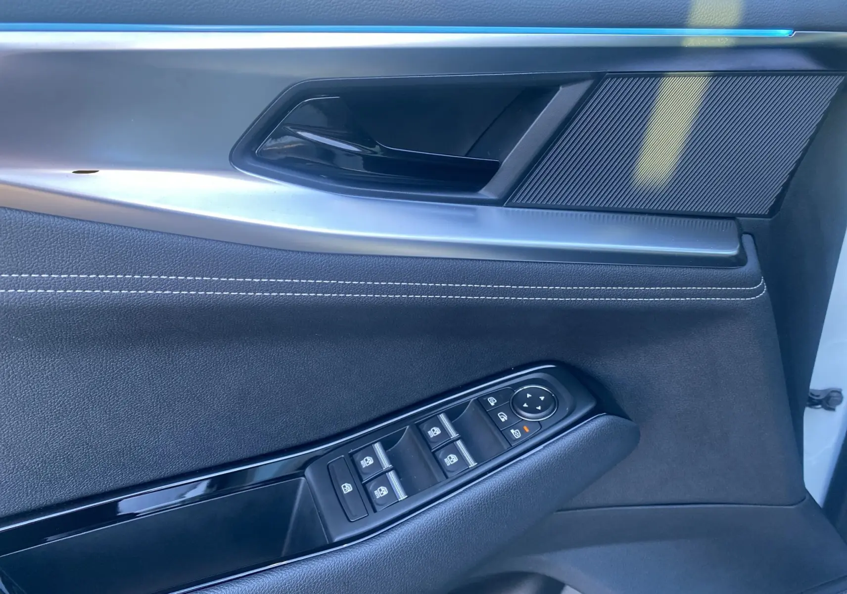 Gros plan sur la porte intérieure côté gauche du Renault Austral blanc nacré, avec commandes de vitres et poignée noire.