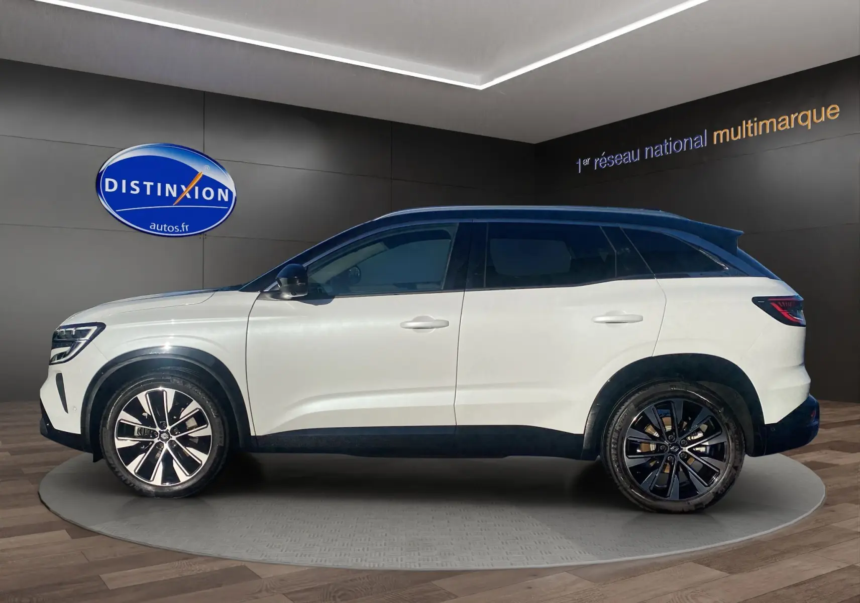 Vue de profil côté gauche du Renault Austral blanc nacré avec toit noir et jantes alu 19 pouces dans un showroom.