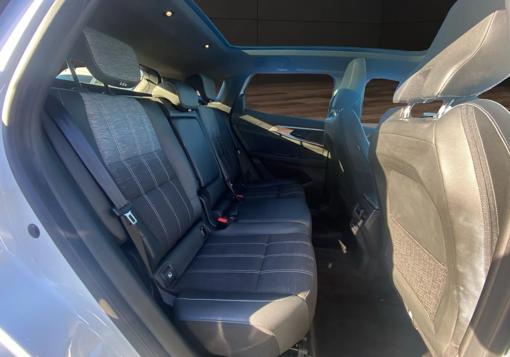 Vue intérieure côté gauche des sièges arrière noirs du Renault Austral 2025 avec toit panoramique et lumière naturelle.