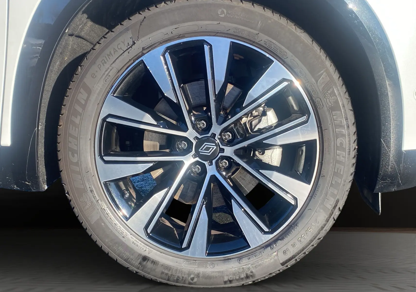 Gros plan sur la jante alu 19'' noire et argentée du Renault Austral blanc nacré, roue avant côté gauche.