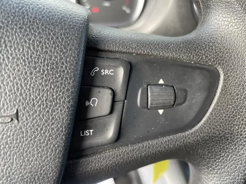 Gros plan sur les commandes au volant du Peugeot Expert Fourgon gris métal, boutons SRC, LIST et molette de réglage.