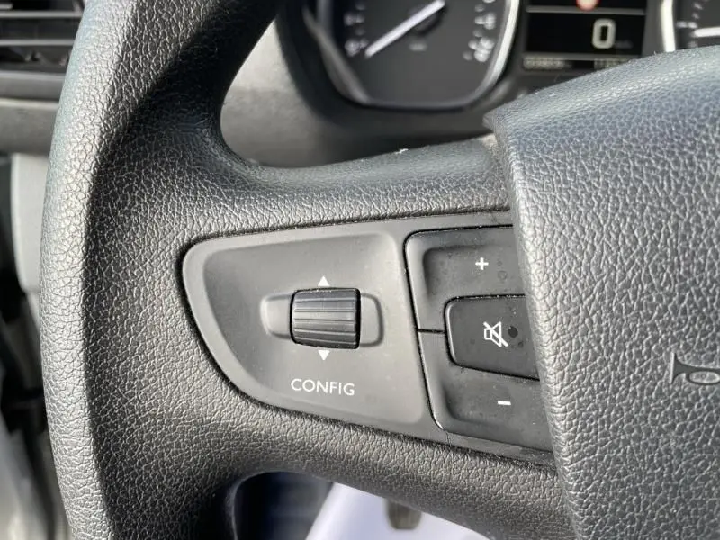 Gros plan sur les commandes gauche du volant du Peugeot Expert Fourgon gris métal, bouton de configuration et réglage du volume visibles.